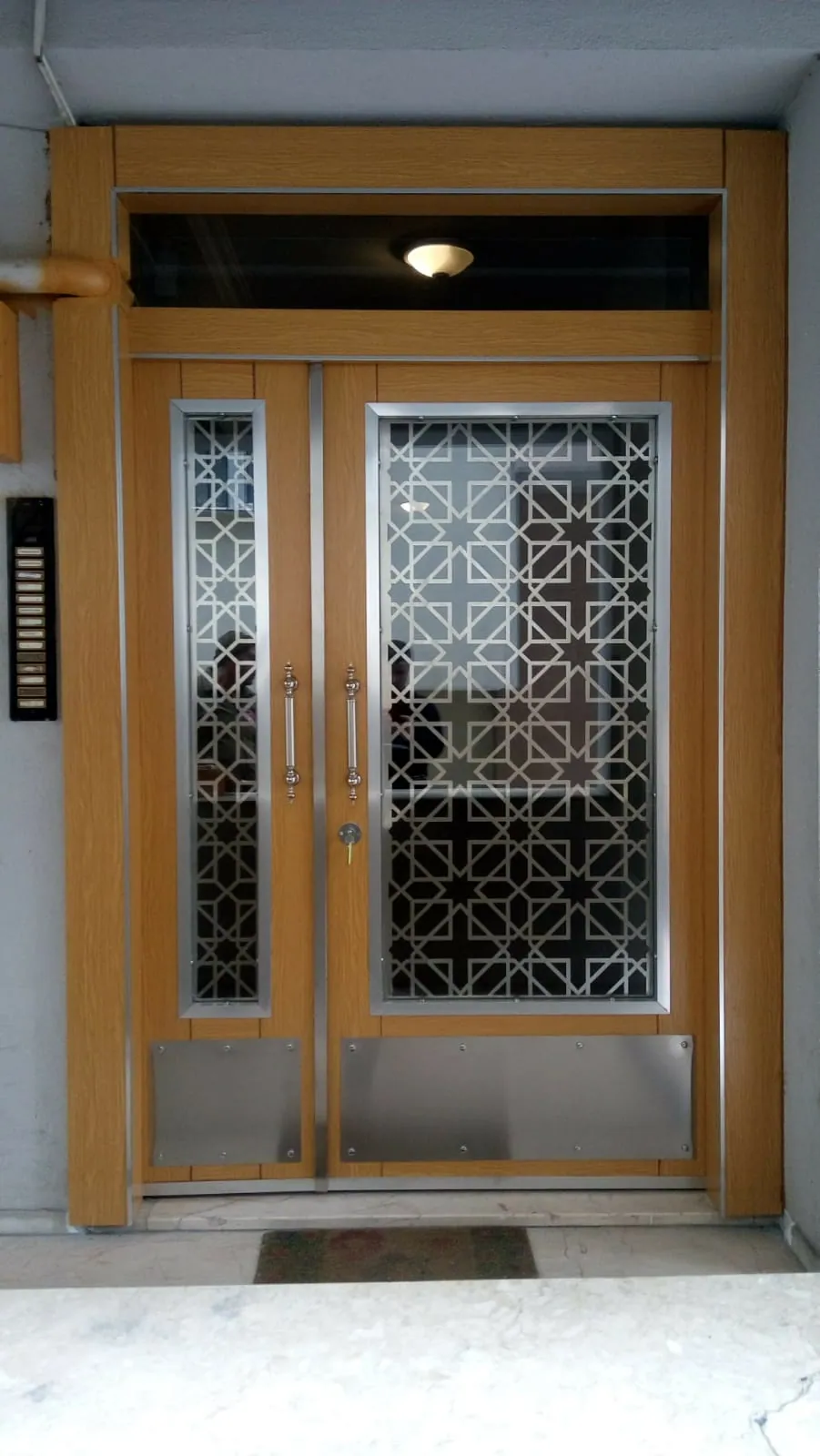 Ahşap kaplama ve ferforje panelli apartman giriş kapısı