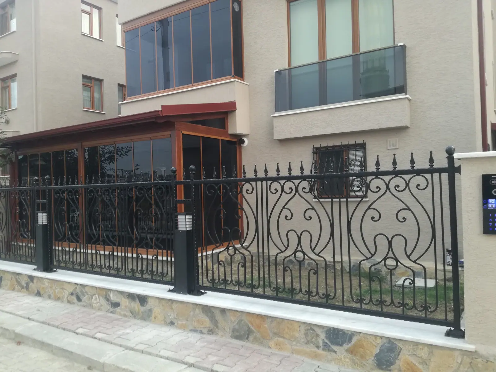 Yeni yapılmış binanın önünde kıvrım desenli bahçe çiti ve korkuluk