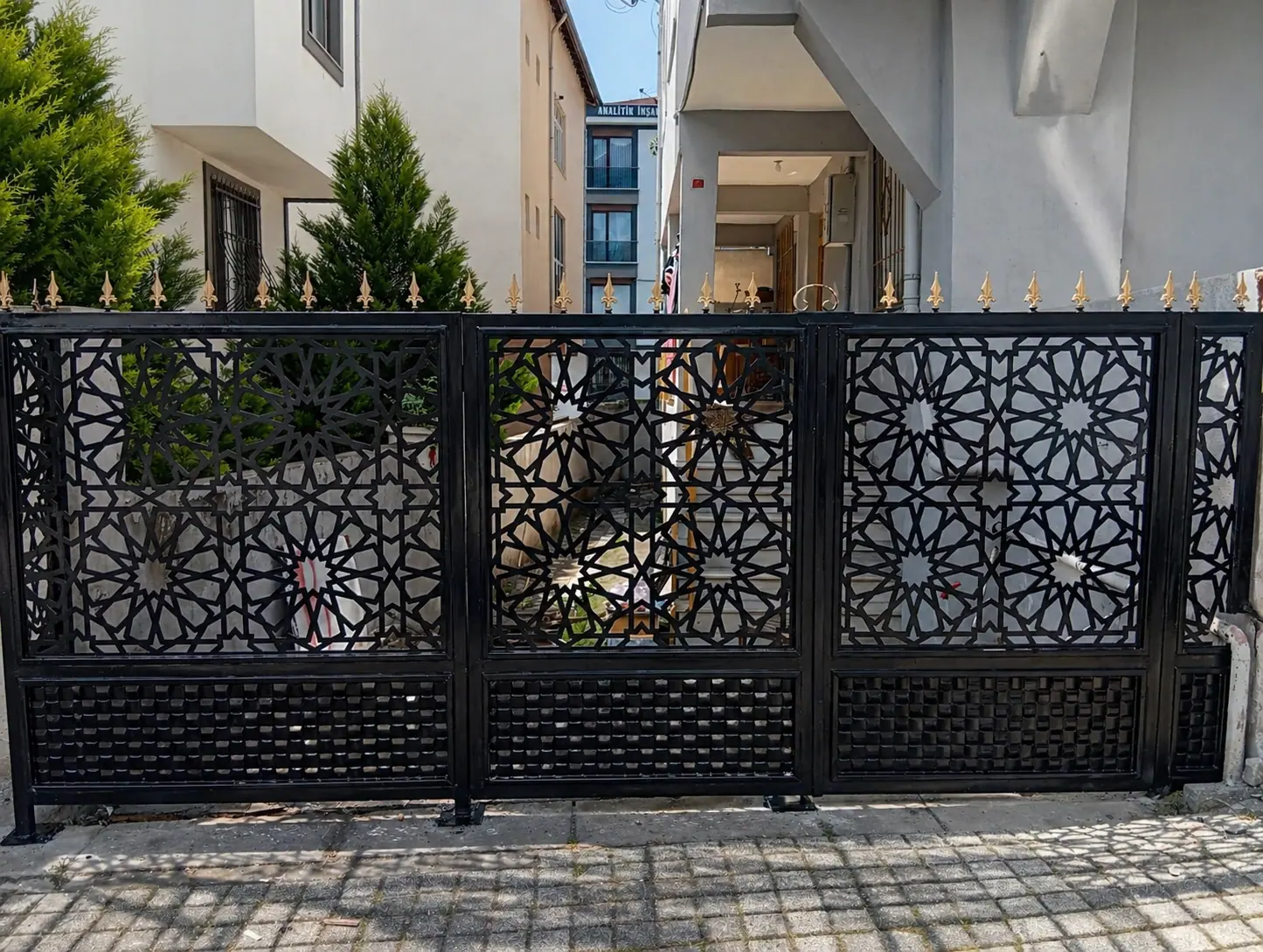 Villa bahçesine yapılmış, lazer kesim geometrik panelli geniş çift kanat ferforje bahçe kapısı